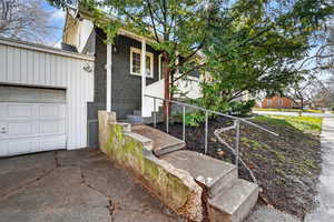 View of side of home with brick siding, board and batten siding, driveway, and an attached garage