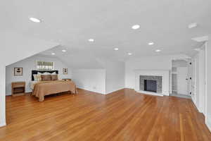Bedroom with light wood-style flooring, a fireplace, and recessed lighting
