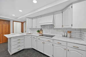 Kitchen with light stone countertops, a peninsula, white cabinetry, tasteful backsplash, and recessed lighting