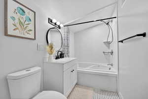 Bathroom featuring vanity, shower / tub combo, and a textured ceiling