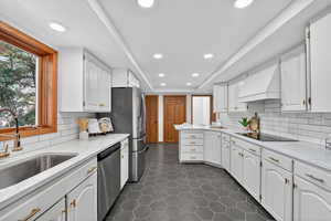 Kitchen featuring light stone counters, a tray ceiling, white cabinetry, stainless steel appliances, and recessed lighting