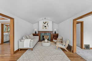 Living room with light wood-style floors, a fireplace, a barrel ceiling, and a textured ceiling