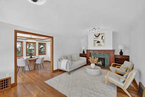 Living room with light wood finished floors, a brick fireplace, hanging lights, and a barrel ceiling