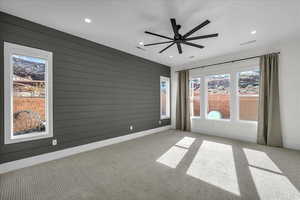 Unfurnished room with a ceiling fan, light colored carpet, wood walls, and recessed lighting
