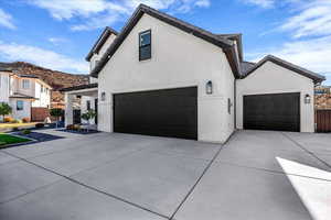 View of front of house with brick siding, driveway, stucco siding, and a garage