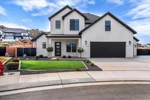 Modern inspired farmhouse with a standing seam roof, concrete driveway, brick siding, and stucco siding