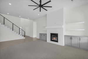 Unfurnished living room featuring a ceiling fan, a glass covered fireplace, recessed lighting, and light carpet