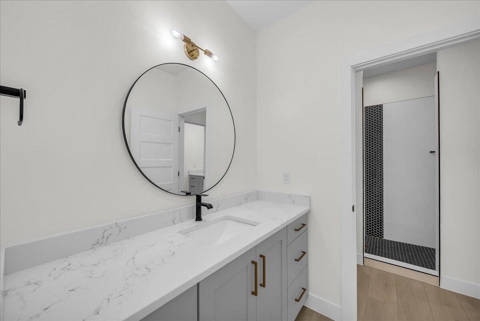 Bathroom featuring vanity, walk in shower, and light wood-style flooring