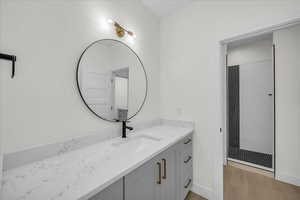 Bathroom featuring vanity, walk in shower, and light wood-style flooring