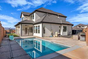Back of house featuring a patio, a fenced backyard, a tile roof, and stucco siding