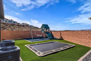 View of playground featuring a fenced backyard, a trampoline, and a patio area