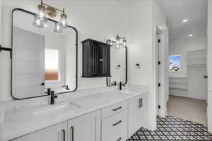 Bathroom featuring double vanity, a spacious closet, recessed lighting, and light flooring