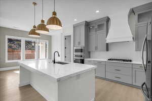 Kitchen featuring gray cabinets, pendant lighting, light stone counters, and light wood-type flooring