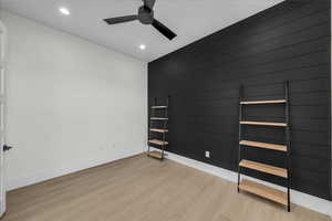 Empty room featuring light wood-style flooring, a ceiling fan, recessed lighting, and an accent wall