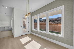 Unfurnished dining area featuring light wood-style floors and suspended lighting