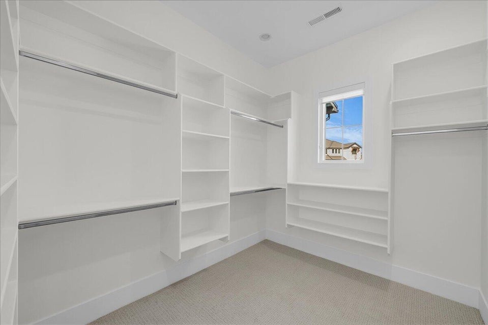 Walk in closet featuring light colored carpet