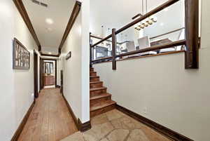 Staircase with ornamental molding, stone finish flooring, and recessed lighting