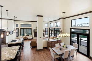 Dining area with dark wood-style flooring, a high ceiling, ornamental molding, and recessed lighting