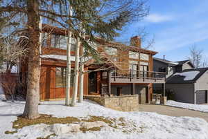 Snow covered property featuring an attached garage and a chimney