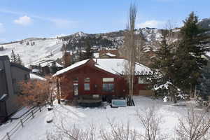 Snow covered property featuring a chimney and a mountain view