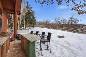 Snow covered patio with a fenced backyard, a patio, and an outdoor kitchen
