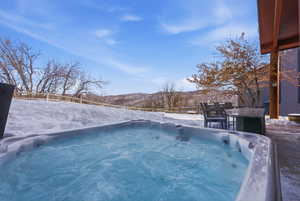 Snow covered pool with a mountain view, a hot tub, and a pool