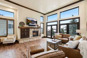 Living room featuring a fireplace, hardwood / wood-style floors, a high ceiling, ornamental molding, and recessed lighting