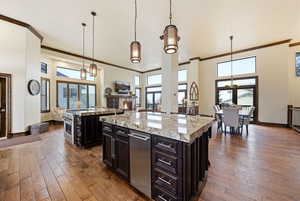 Kitchen featuring crown molding, a large island, dark wood-type flooring, a high ceiling, and a warm lit fireplace