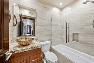 Bathroom featuring tile walls, vanity, tiled shower / bath, and recessed lighting