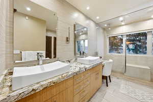Bathroom featuring tile walls, double vanity, and a shower stall