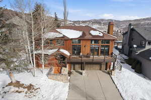 Chalet / cabin featuring a deck with mountain view, a chimney, an attached garage, and concrete driveway