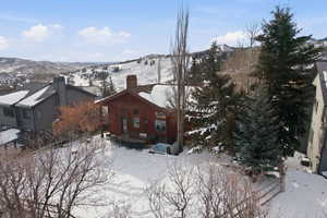 View of snowy exterior with a chimney and a mountain view