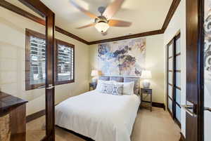 Carpeted bedroom featuring ornamental molding, a ceiling fan, and french doors