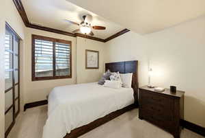 Bedroom with light carpet, ceiling fan, and crown molding