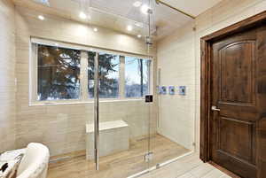 Full bath featuring a shower stall and tile walls