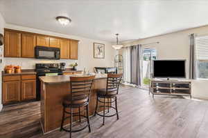 Kitchen featuring dark countertops, wood finish cabinets, black appliances, and a center island