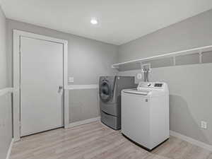 Laundry room featuring light wood-style floors and washing machine and dryer