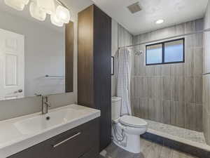 Full bathroom featuring vanity, a stall shower, a textured ceiling, and wood tiled floors
