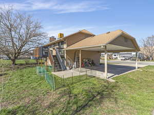 View of home's exterior with a carport, a lawn, a shingled roof, a patio, and a deck