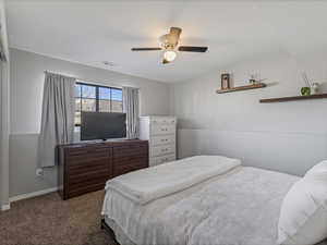 Bedroom with dark carpet and a ceiling fan