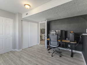 Office area with light wood-style flooring and a textured ceiling