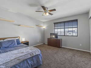 Bedroom with dark colored carpet, a ceiling fan, and a textured ceiling