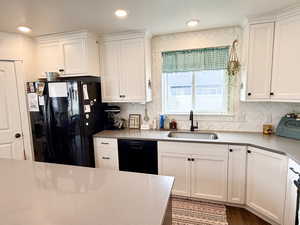Kitchen featuring white cabinets, black appliances, and dark wood finished floors