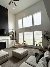 Carpeted living area with a high ceiling, a fireplace, ceiling fan, and recessed lighting