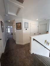 Hall with dark carpet and an upstairs landing