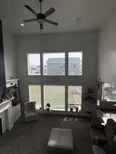 Living area featuring a high ceiling, ceiling fan, healthy amount of natural light, dark colored carpet, and recessed lighting