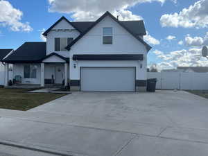 View of front of home with a gate, covered porch, driveway, board and batten siding, and a garage