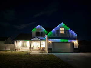 View of front of home with covered porch, concrete driveway, board and batten siding, a gate, and an attached garage