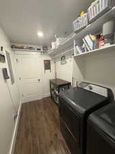 Laundry room with dark wood finished floors, washer and dryer, and electric panel
