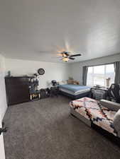 Bedroom with carpet, a ceiling fan, and a textured ceiling